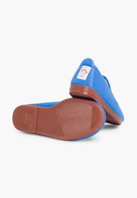 Blauwe canvas instap schoenen met een rubberen zool, voorzien van een afgeronde neus, textuurdetails op de zool en een label met de tekst "made in Spain."