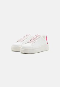 Baskets blanches avec des accents roses, dotées de lacets à motifs, d'une tige synthétique lisse, d'un bout arrondi et d'une semelle épaisse et texturée.
