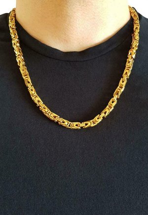 Collier en chaîne dorée avec des maillons entrelacés au design plat, porté sur une chemise noire, montrant une finition brillante et polie.