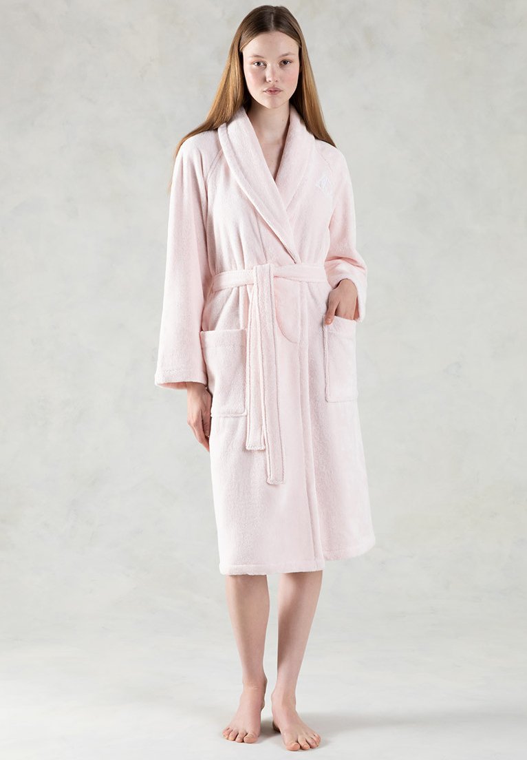 Accappatoio rosa in peluche con colletto a scialle, cintura di legatura e due tasche frontali; presenta una texture morbida e una lunghezza midi.