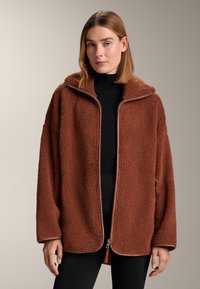 Brown fleece jacket with a zip front, oversized hood, and textured feel. Features a contrasting zipper and side pockets.