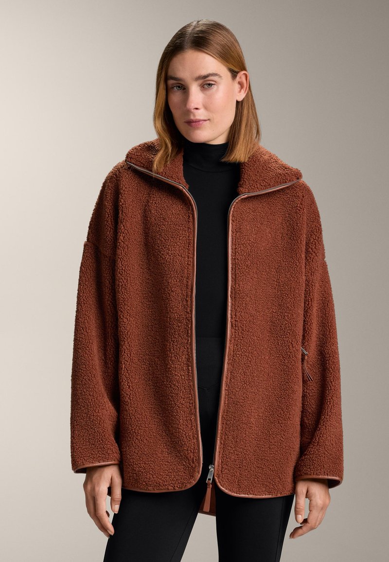 Brown fleece jacket with a zip front, oversized hood, and textured feel. Features a contrasting zipper and side pockets.