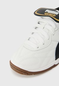 Hvite sneakers med svarte detaljer, med teksturert overdel, rund tå og snøring. Inkluderer en merket tunge og gummiai.