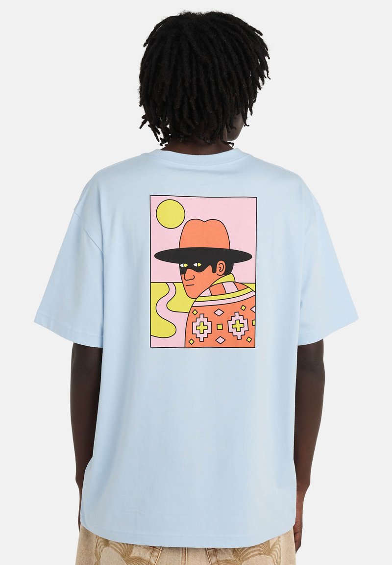 Hellblaues Baumwoll-T-Shirt mit großem Grafikdruck auf der Rückseite, der eine Person mit breitkrempigem Hut vor farbenfrohem Hintergrund zeigt.