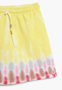 Pantaloncini gialli tie-dye con vita elastica e coulisse regolabile. Il tessuto presenta un motivo sfumato con accenti rosa e marroni.