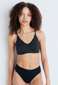Brassière noire avec des coussinets en triangle et des bretelles fines, assortie à un slip de bikini taille haute. Tissu lisse et design sans couture.