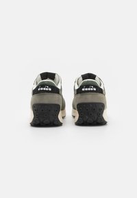 Scarpe da ginnastica verdi e nere con una tomaia texture, fodera morbida, dettagli neri nel tallone e una suola in gomma con motivi circolari.