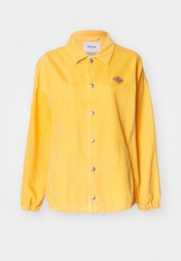 Gul denimjakke med klassisk krage, frontknapper, sidelommer og elastiske mansjetter. Har en liten logopatch på brystet.