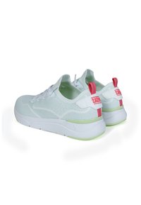 Sneakers bianchi in maglia con finitura testurizzata, suola verde e linguetta rossa sul tallone; presentano lacci e un marchio sul lato.