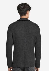 Dunkelgrauer Blazer aus strukturiertem Stoff, mit Reverskragen und langen Ärmeln. Verfügt über einen Mittelrücken-Schlitz für mehr Bewegungsfreiheit.