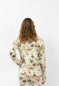 Blumenmuster Langarmshirt in pastellfarbenen Tönen mit Pfingstrosen-Design. Weicher, strukturierter Stoff. Lockere Passform mit abgerundetem Saum und gesenkten Schultern.