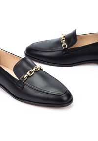 Mocasines de cuero negro con un acento de cadena dorada en el empeine, superficie texturizada, puntera afilada y diseño minimalista.