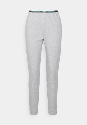 Graue Sweatpants mit einem elastischen Bund, der mit schwarzen und grünen Streifen sowie einem Logo-Tag versehen ist. Taillierter Beinabschluss mit gerippten Knöcheln.