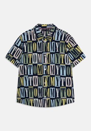 Lyhythihainen napillinen paita, jossa on monivärinen kuvio sanasta "TOMMY" eri fonteilla tummalla taustalla.