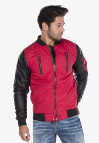 Rode bomberjack met zwarte leren mouwen, ritssluitingen, geribbelde kraag en manchetten, slank ontwerp en sluiting met rits aan de voorkant.