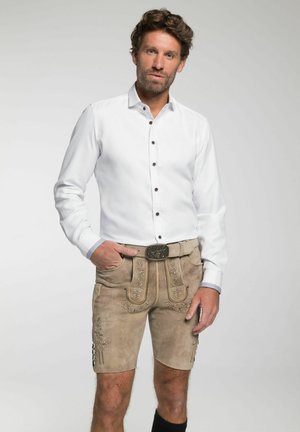 Weißes Hemd mit braunen Knöpfen, kombiniert mit beigen Lederhosen, die mit gestickten Blumenmustern und einem dekorativen Gürtel verziert sind.