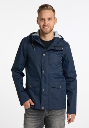 Marineblå vandtæt jakke med hætte, der har en grå inderside, trykknapper og to forlommer. Glat tekstur og afslappet design.