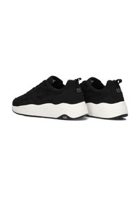 Zwarte sneakers met een gestructureerde bovenkant, voorzien van een dikke witte zool en subtiele branding op de hiel. Vetersluiting met een trekhaak aan de achterkant.