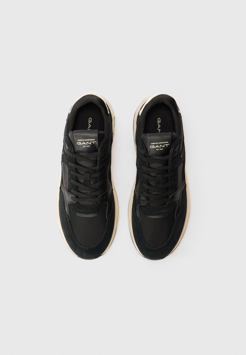Czarne buty sportowe z mixem gładkich i teksturowanych materiałów, z kremową podeszwą środkową i detalami logo na języku.