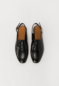 Mustad nahast slingback kingad ruudu otsaga, dekoratiivse õmblusega ja väikese pandlaga rihmal. Pruun sisetald.