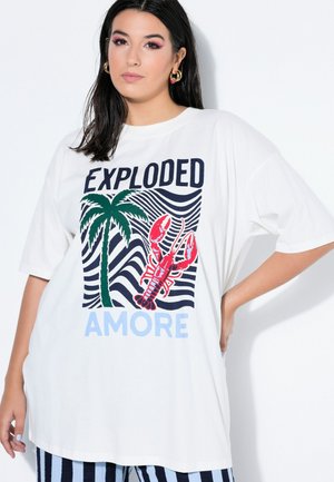 Jonge vrouw met lang donker haar draagt een oversized wit T-shirt met palmboom, rode kreeft illustratie en tekst "EXPLODED AMORE."
