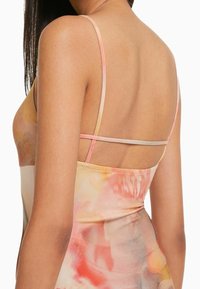 Sukienka z satynowego materiału w kolorach wodnych w odcieniach różu, pomarańczy i kremu. Posiada cienkie ramiączka i dopasowany krój.