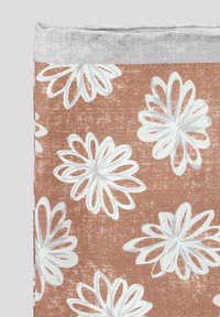 Brązowa tkanina o teksturowanym wykończeniu, z dużymi białymi wzorami kwiatów z warstwowymi płatkami, otoczona jaśniejszą ramką.