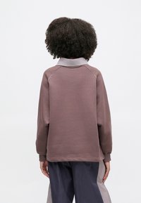 Πουλόβερ σε απαλό μωβ με γκρι γιακά, διαθέτει ριμπ μανσέτες και άνετη εφαρμογή, με ελάχιστες λεπτομέρειες ραφής στο πίσω μέρος.