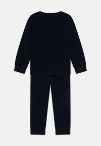 Marineblauw pyjama-set met een lange mouw top en bijpassende broek. Zacht, glad stof met aansluitende manchetten bij de mouwen en enkels.