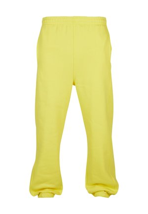 Żółte dresy wykonane z miękkiej tkaniny, z elastycznym pasem, zwężającymi się nogawkami i elastycznymi manszetami przy kostkach.
