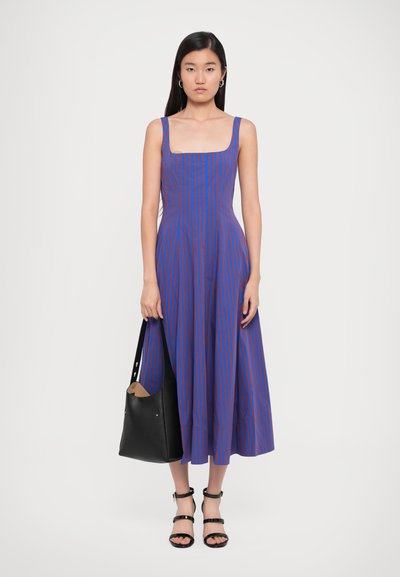 Blue and purple striped midi dress with a square neckline, fitted bodice, and flared skirt. Black tote bag and strappy sandals complete the look.