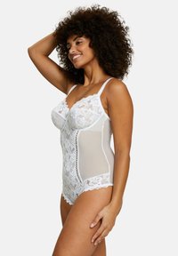 Body en dentelle blanche avec panneaux transparents, soutien-gorge à armatures, bords festonnés et bretelles réglables. Présente un motif floral en dentelle et une texture semi-transparente.