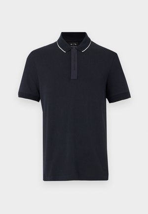 Polo bleu marine à manches courtes avec bordure de col blanche et patte de boutonnage dissimulée, présenté sur un fond neutre.