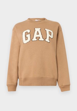 Lichtbruine rondehals sweater met grote witte "GAP" letters omrand door donkerbruin op de borst, lange mouwen en geribbelde manchetten en zoom.