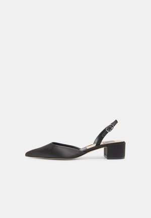 Zapato negro de punta puntiaguda con tiras traseras ajustables, tacón bajo tipo bloque y hebilla ajustable, sobre fondo blanco.