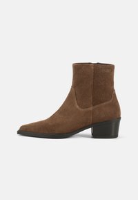 Bota de tobillo de ante marrón con punta afilada y tacón bajo cuadrado. Presenta costuras mínimas y un cierre de cremallera en la parte posterior.