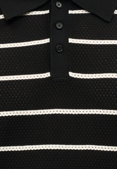 Μαύρο πλεκτό πόλο με λευκές οριζόντιες ρίγες και τρία μαύρα κουμπιά στην πλάκα.