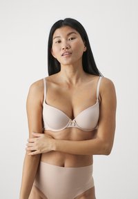 Light pink bra with smooth fabric, underwire support, adjustable straps, and a center bow detail, paired with matching high-waisted briefs.