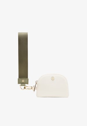 Valkoinen vetoketjullinen pussi, joka on valmistettu pehmeästä materiaalista ja jossa on pyöristetty yläosa. Pussi on kiinnitetty oliivinvihreään nylonhihnaan, jossa on kultaiset soljet ja metalliosat.