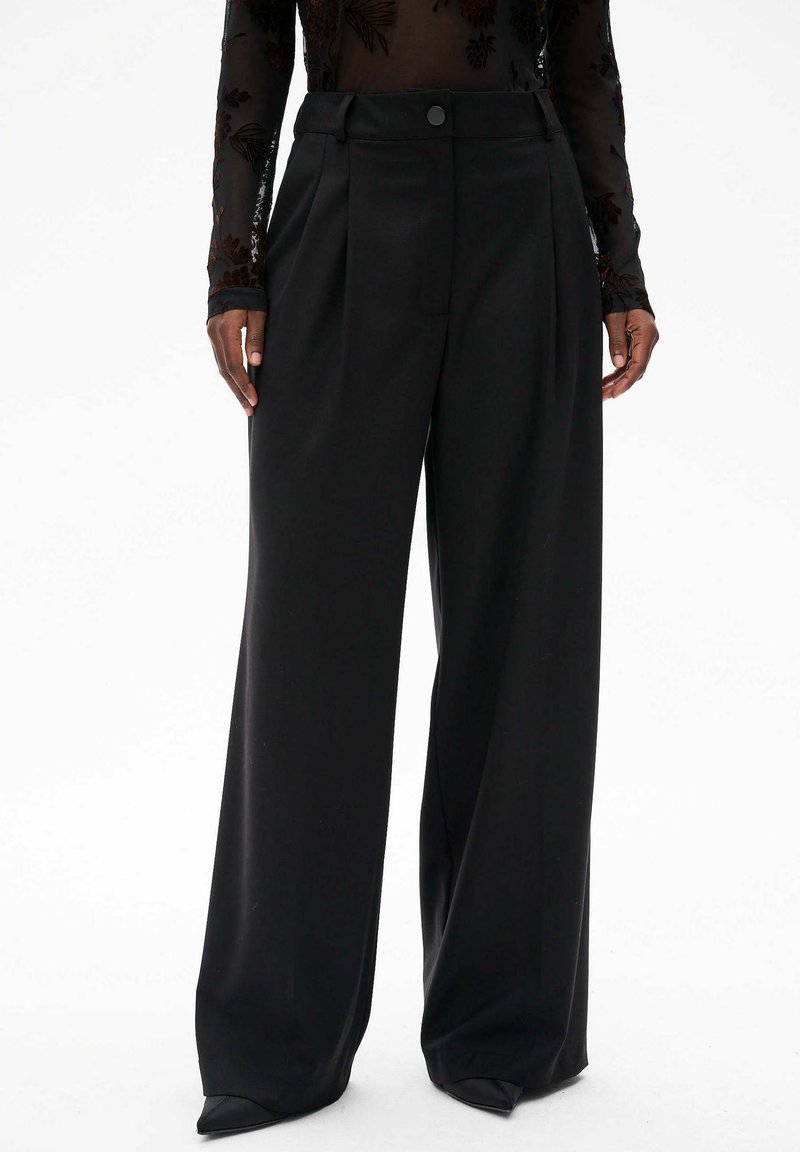 Zwarte wijde broek met een sleek, gladde textuur en voorplooien. Heeft een enkele knoopsluiting bij de taille en een hoge taille pasvorm.