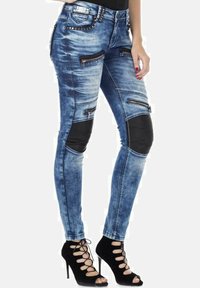 Skinny jeans van denim met gescheurd blauw stof, meerdere ritszakken, zwarte faux leren accenten op de knieën en een gestifte tailleband.