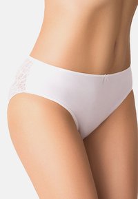 Mutande di cotone bianche con dettagli in pizzo sui lati, caratterizzate da una texture morbida e liscia e un design a vita bassa. Fiocco decorativo sul davanti.
