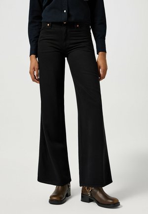 Black wide-leg jeans made from denim with a smooth texture, featuring orange stitching and button details, paired with brown ankle boots.