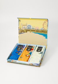 Three pairs of socks in a decorative box. Colors: blue with cartoon, orange with pattern, and white with green accents. Box features a beach scene.
