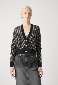 Μαύρο και κρεμ καπλάνι με σχέδιο, με βαθύ V-λαιμόκοψη, διαθέτει τέσσερα κουμπιά, ριμπ μανσέτες και κοντή σ χεδίαση, συνδυασμένο με τζιν φούστα.