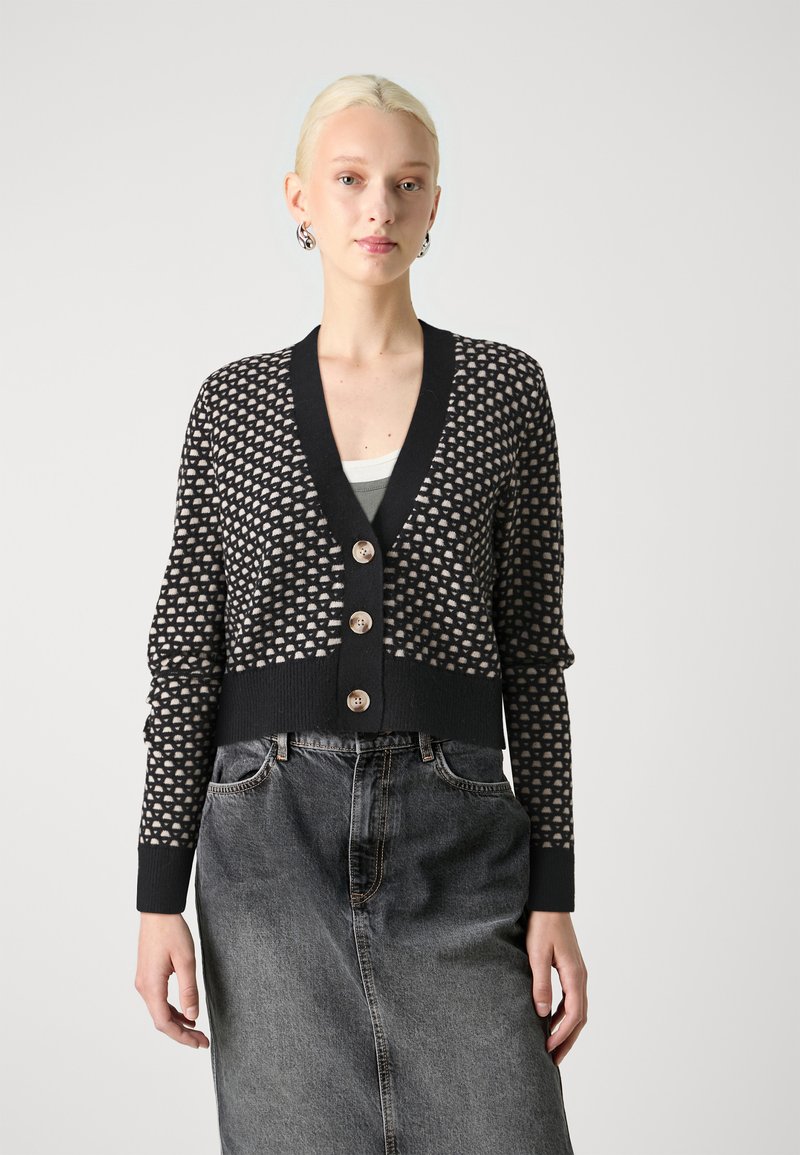 Μαύρο και κρεμ καπλάνι με σχέδιο, με βαθύ V-λαιμόκοψη, διαθέτει τέσσερα κουμπιά, ριμπ μανσέτες και κοντή σχεδίαση, συνδυασμένο με τζιν φούστα.