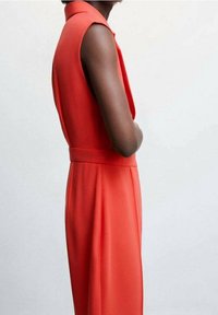 Czerwona sukienka bez rękawów z dopasowaną talią i rozkloszowanym dołem. Gładka faktura i minimalistyczny design, podkreślający czyste linie i kolor.