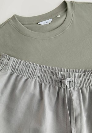 Olivovo zelené tričko s okrúhlym výstrihom a šedé elastické nohavice so šnúrkou. Mäkko z tkaniny s hladkou textúrou.