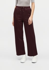 Μπέρτζιν παντελόνια με φαρδιά λεκάνη, με υφασμένη μέση και ρυθμιζόμενο κορδόνι. Συνδυάζονται με λευκά, μίνιμαλ αθλητικά παπούτσια.