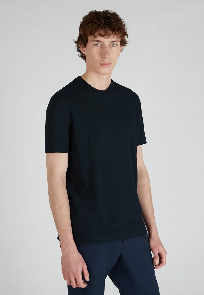 Camiseta negra de cuello redondo, hecha de algodón, con mangas cortas y un diseño liso. Textura suave con un corte regular.